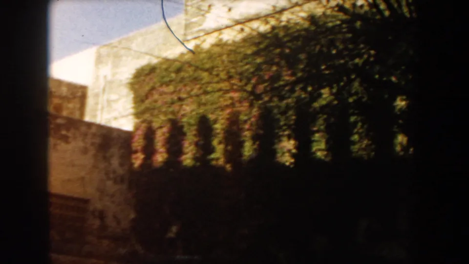 1959 Casablanca home-movie view of a vine-covered masonry building with arched openings and tree shadows.