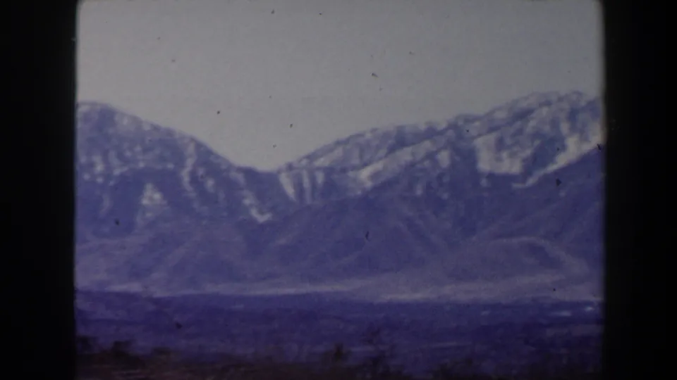 1958 8mm Las Vegas-area landscape with snow-lined mountains, open valley floor, and visible film wear.