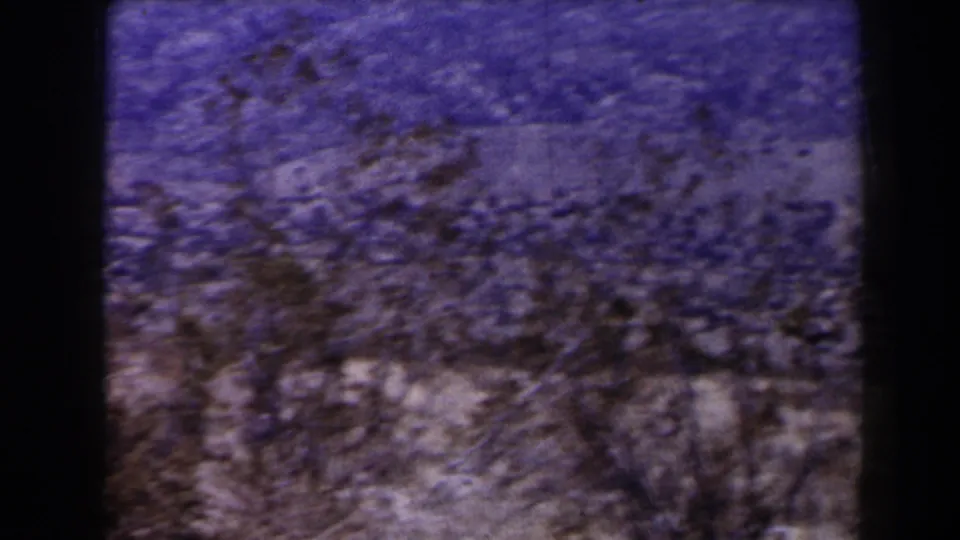 Soft, handheld 8mm frame of desert brush and a brown hillside during a pan across the Las Vegas-area landscape.