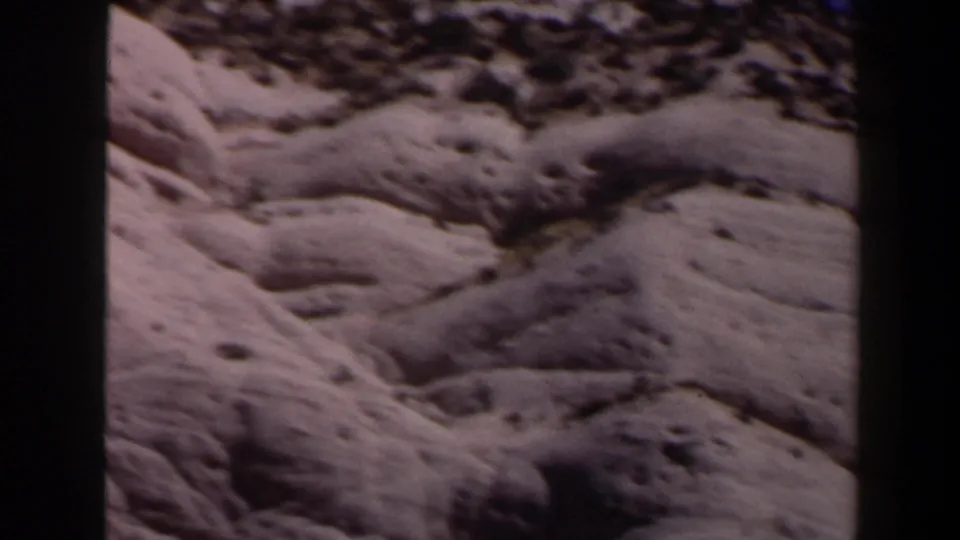 1958 Las Vegas-area 8mm frame showing a barren sandy hillside with ridges, scrub, and soft home-movie blur.