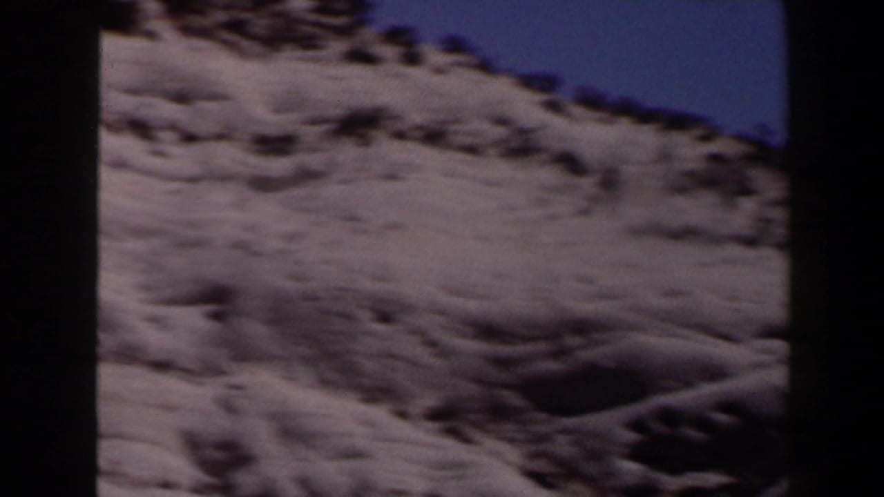 1958 Las Vegas-area desert hillside beneath a clear blue sky, filmed from a moving 8mm home-movie camera.