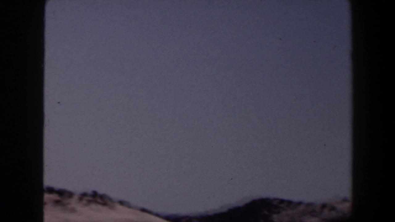 Dark-edged frame with pale sky above distant low mountain ridges.