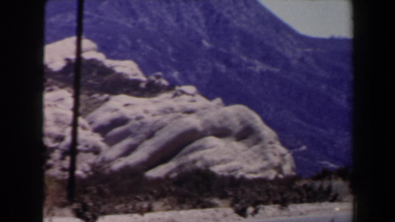 Pale rock formations and distant mountains with a dark utility pole at the left edge.