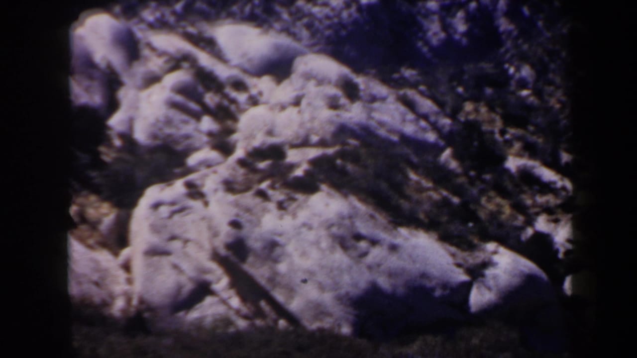 1958 Las Vegas-area 8mm frame with large pale desert boulders, dark brush, and pronounced frame-edge shadow from the scanned film.