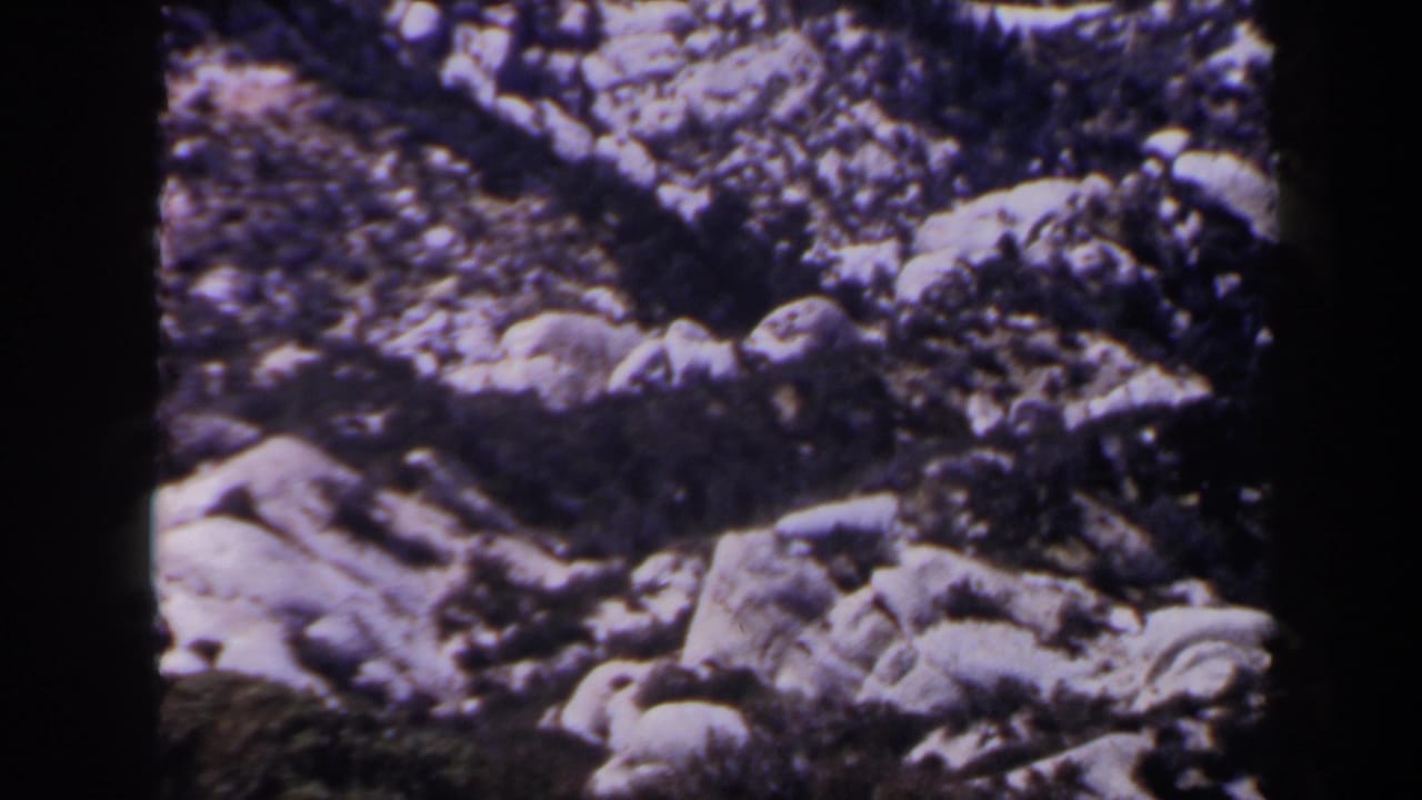 1958 Las Vegas-area 8mm view of clustered desert rocks, irregular pale stone surfaces, and a dark band at the bottom of frame.