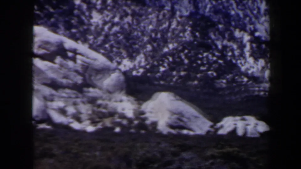 Aged 8mm view of rocks and lingering snow on rugged terrain, with the Las Vegas-area location supported by clip metadata.