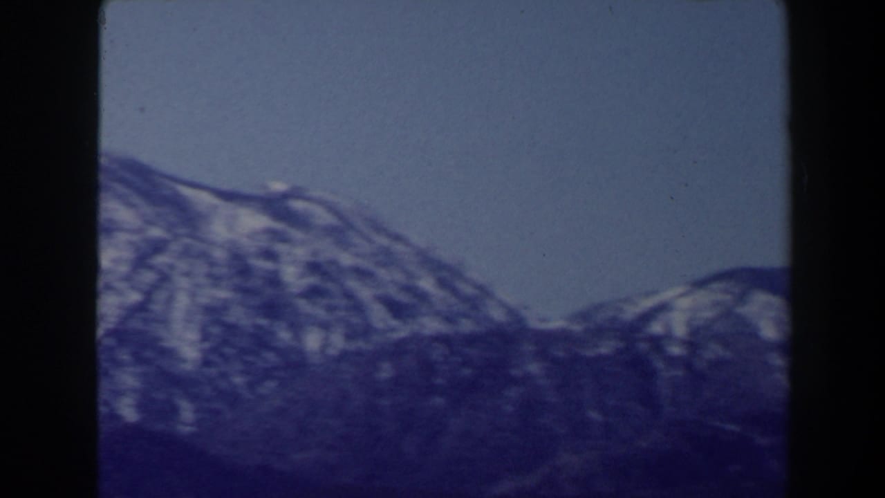 Snow-streaked mountain ridge under blue sky with dark 8mm frame edges.