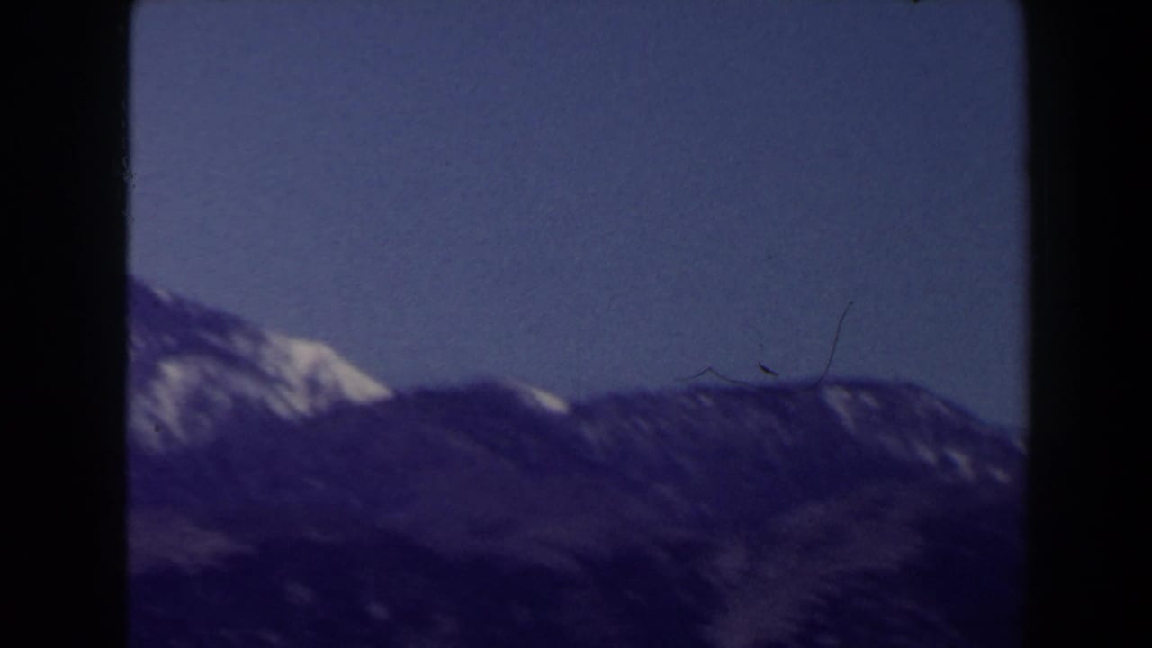 Distant mountain ridge with patches of snow, seen in soft purple-blue 8mm color near Las Vegas in 1958.