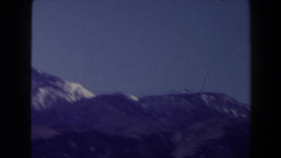 Distant mountain ridge with patches of snow, seen in soft purple-blue 8mm color near Las Vegas in 1958.