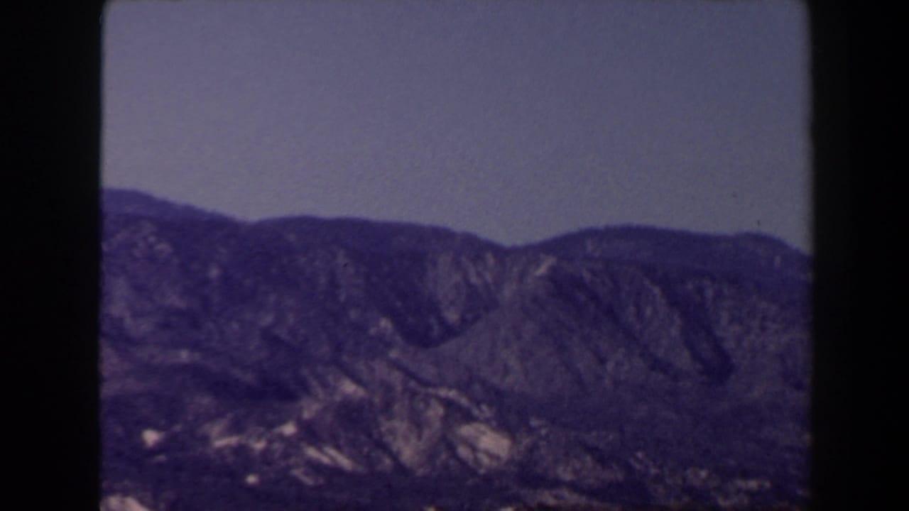 Rugged mountain ridge and foothills beneath a clear sky in a 1958 8mm Las Vegas-area landscape shot.