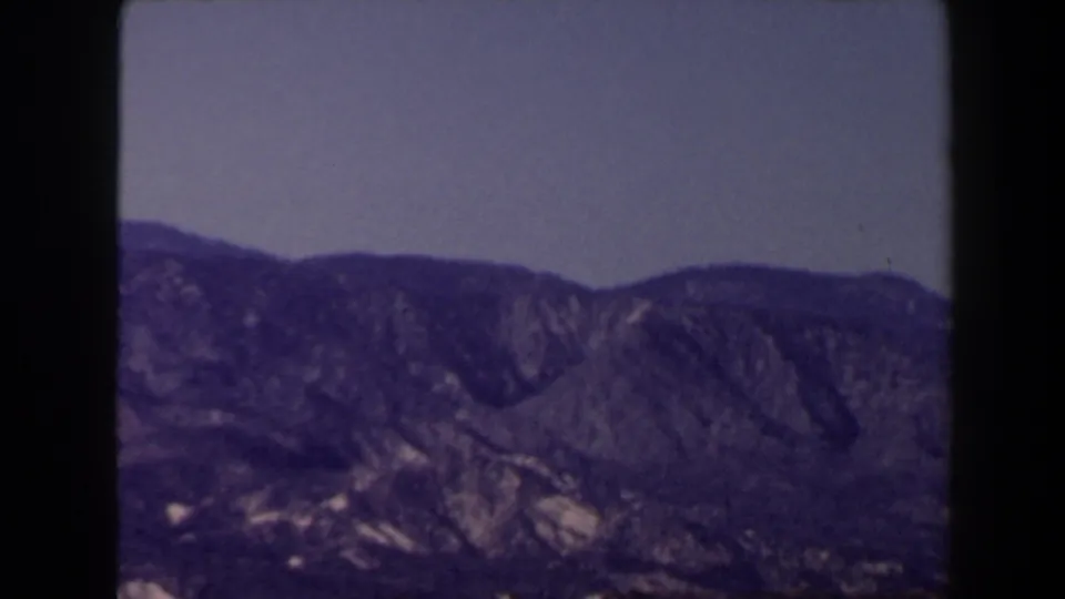 Rugged mountain ridge and foothills beneath a clear sky in a 1958 8mm Las Vegas-area landscape shot.