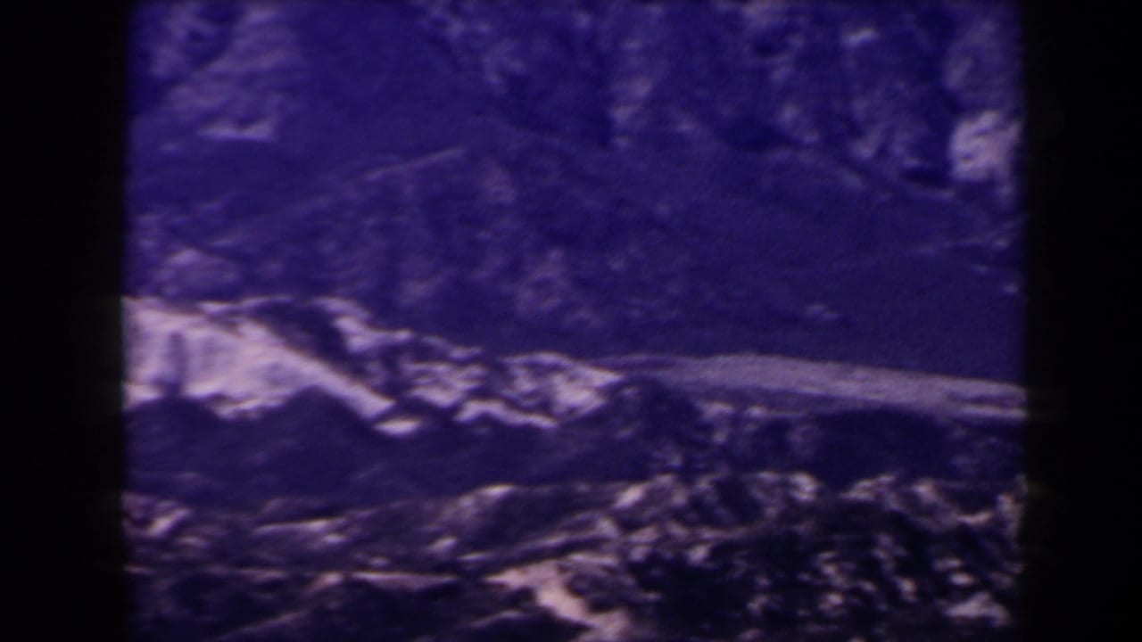 1958 Las Vegas-area 8mm frame showing a broad treeless ridge and pale diagonal rock face in bluish tint.