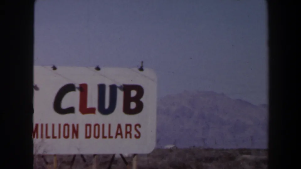 1958 Las Vegas frame with the ADA Club sign cropped to the word “CLUB,” red money-claim text, desert ground, and mountains.