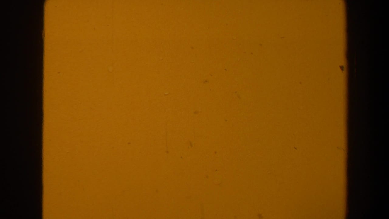 Orange-yellow film frame with dark vertical borders and visible grain.