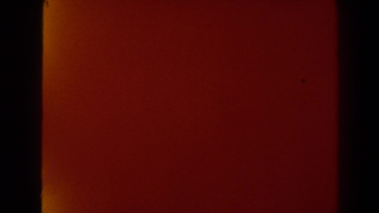 Deep red transitional 8mm frame from the Las Vegas home movie, showing dark side borders and subtle film texture.