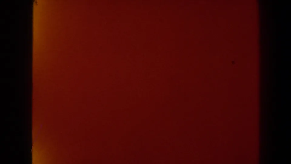 Deep red transitional 8mm frame from the Las Vegas home movie, showing dark side borders and subtle film texture.