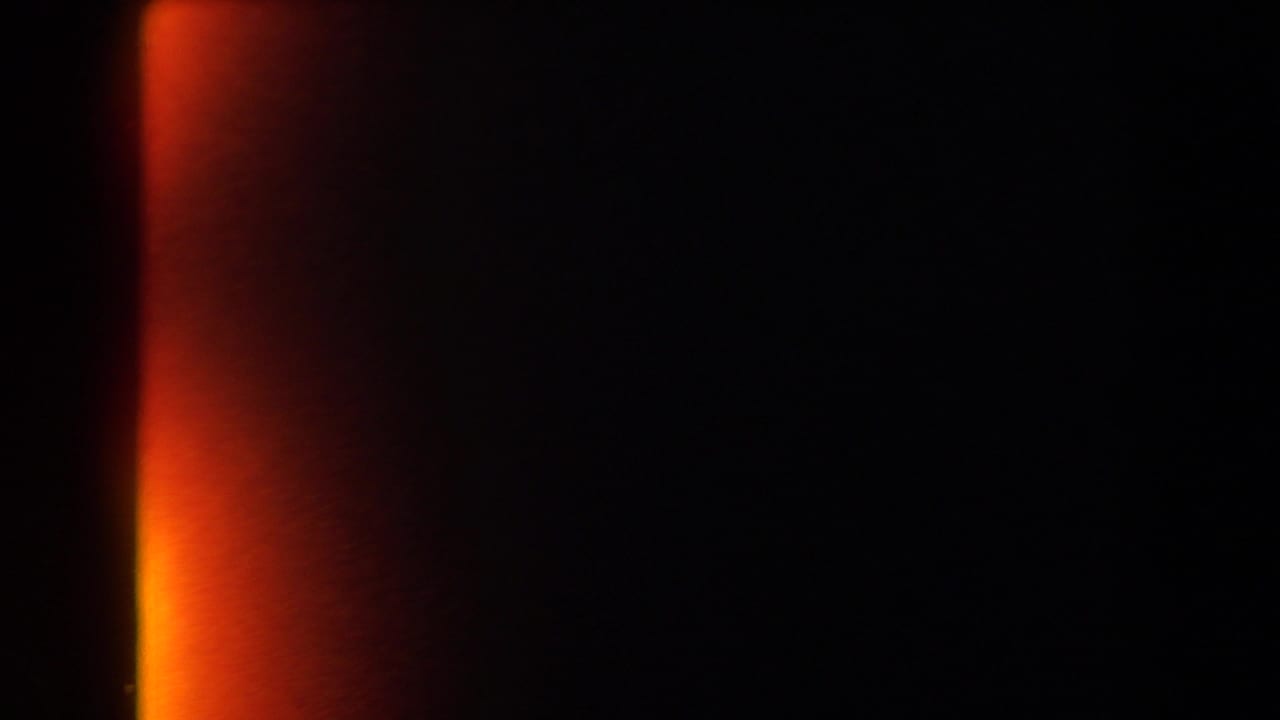 Mostly black 8mm frame with an orange-red light leak at the side, preserving the clip's physical film transition.