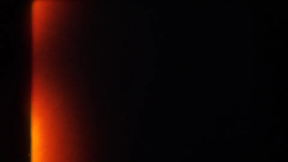 Mostly black 8mm frame with an orange-red light leak at the side, preserving the clip's physical film transition.