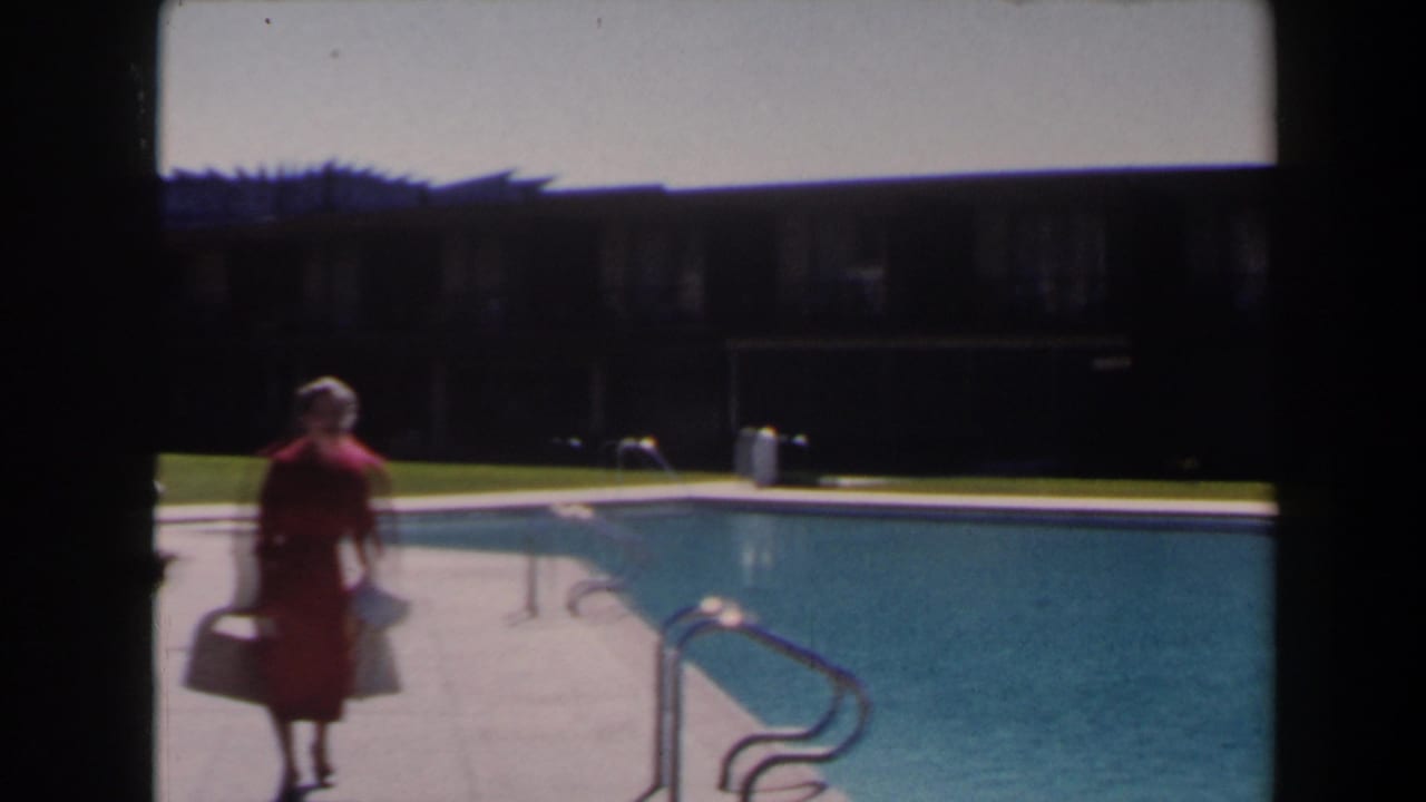The woman in red nears the camera on a bright poolside path in 1958 Las Vegas home-movie footage.