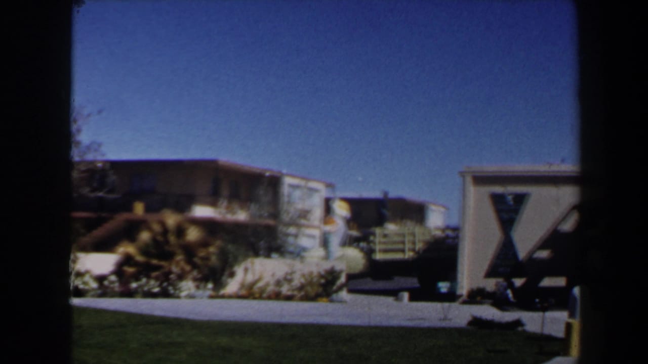 1958 Las Vegas frame showing shrubs, driveway, balcony, residential buildings, and a partial geometric structure at the right edge.