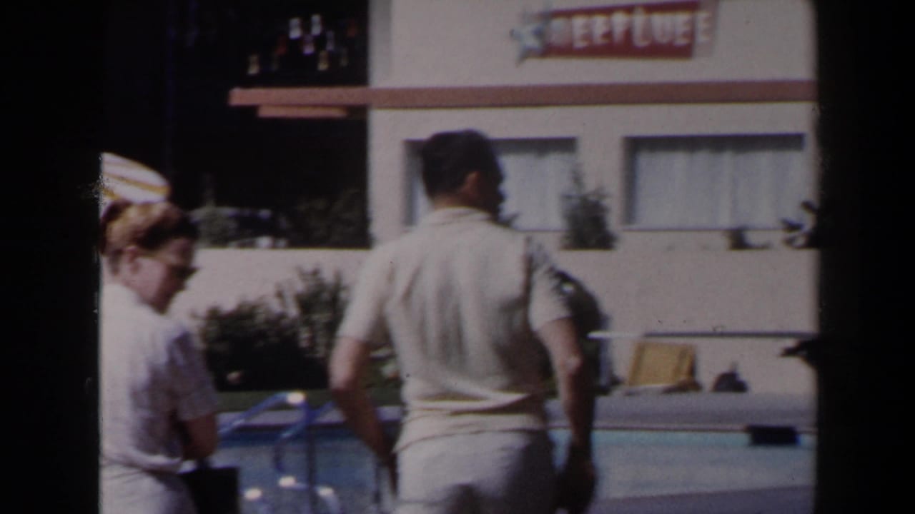 1958 Las Vegas resort poolside frame with adult guests, lounge chairs and a hotel building bearing a visible NEPTUNE sign.