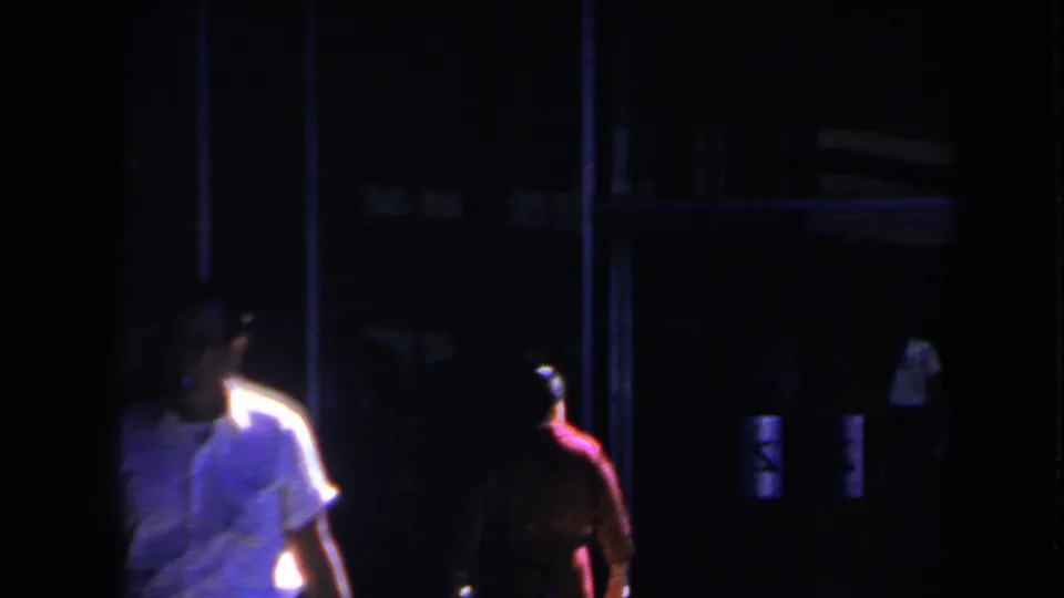 1958 Las Vegas night frame showing people beside a dark entrance with soft focus and colored light.