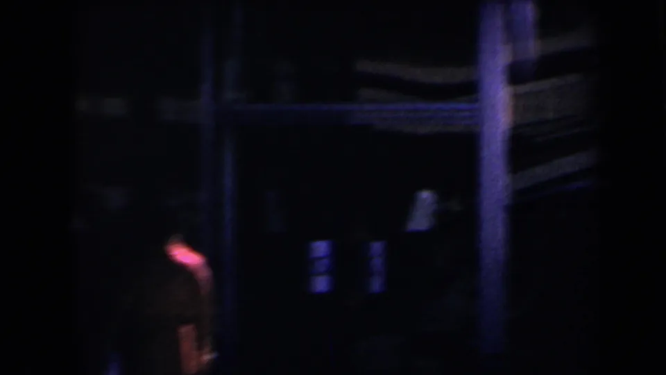 Low-light 1958 Las Vegas street frame with a blurred person near deep shadows and dim building details.