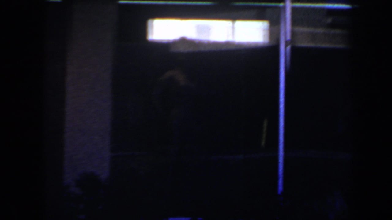 1958 Las Vegas 8mm frame with bright rectangular interior lights and a faint human silhouette against a very dark background.