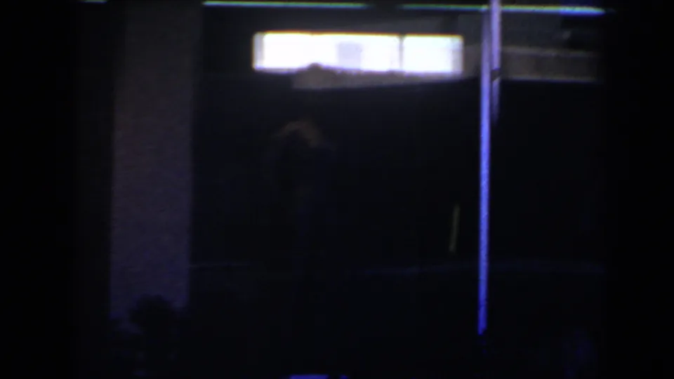 1958 Las Vegas 8mm frame with bright rectangular interior lights and a faint human silhouette against a very dark background.