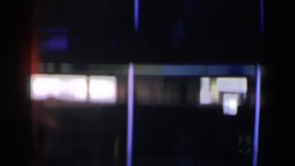 1958 Las Vegas 8mm frame with bright window-like panels, a blue vertical light line, and indistinct shapes in heavy shadow.