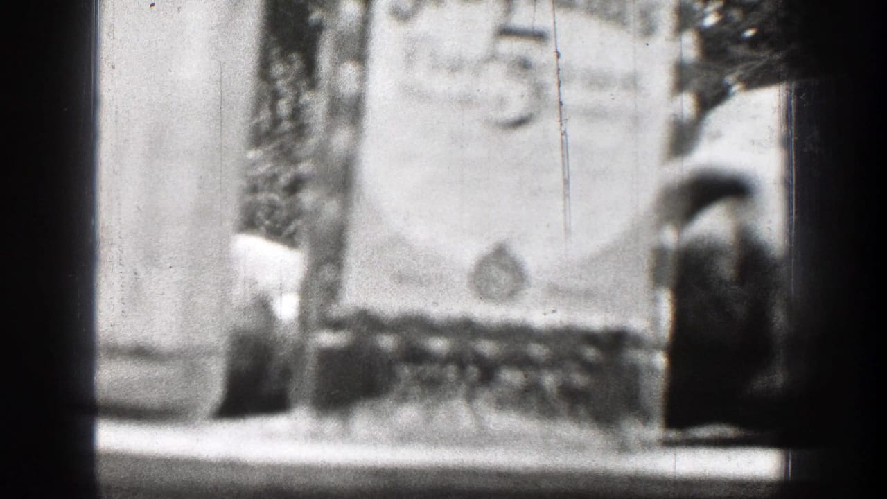 Chelan, Washington 1939 home-movie frame showing bottles on a table and a partly visible deer skull or trophy display in soft focus.