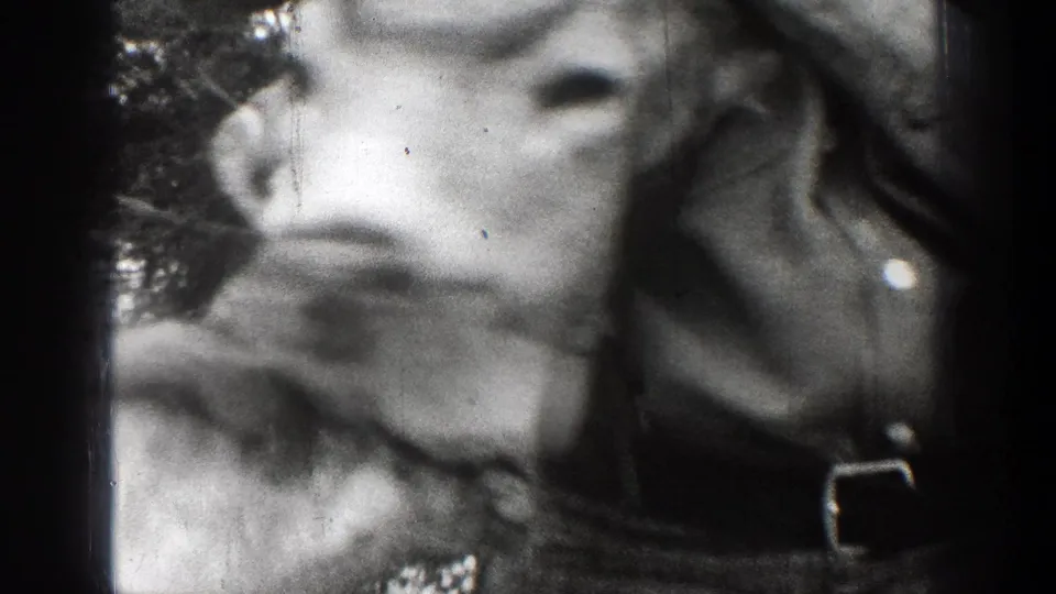 Close 1939 Chelan frame of a deer skull with antlers beside a partially visible adult, rendered in soft black-and-white 8mm texture.