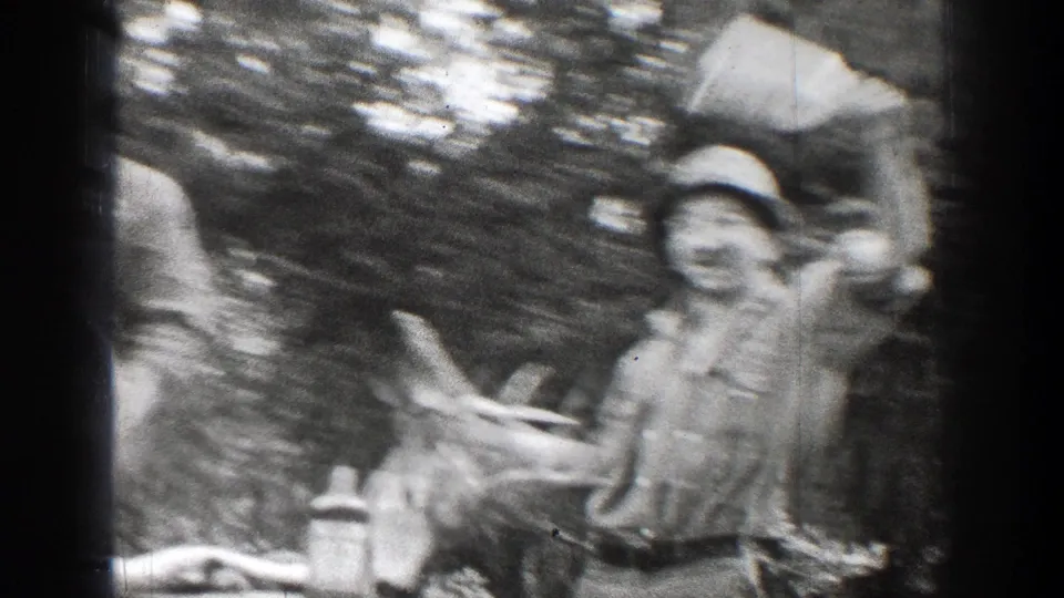 Soft 8mm frame from Chelan showing two adult men moving around the hunted deer in the woods.
