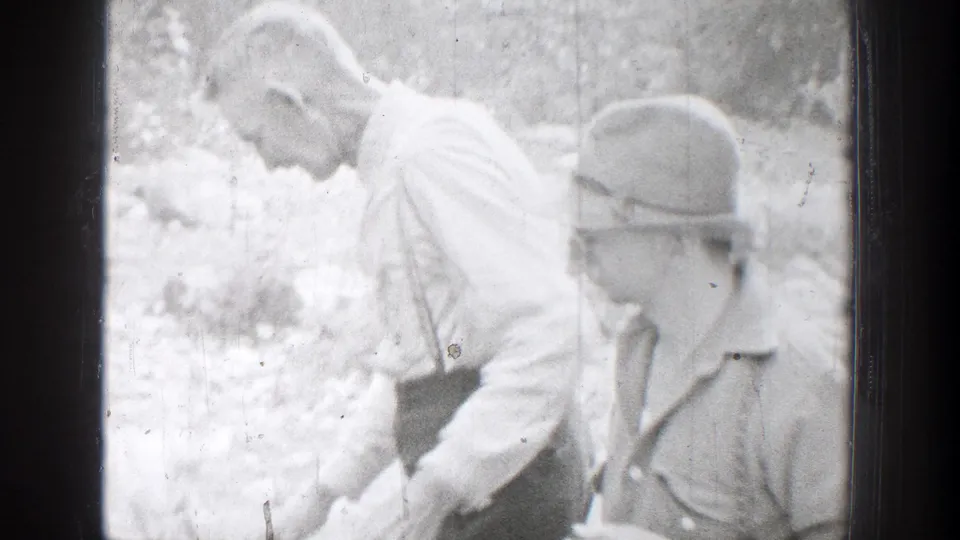 Bright 1939 Chelan home-movie frame showing two adult men working close to the deer during the hunting scene.