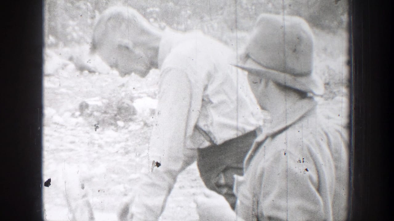 In 1939 Chelan, Washington footage, two men in brimmed hats lean close together in a rocky outdoor area.