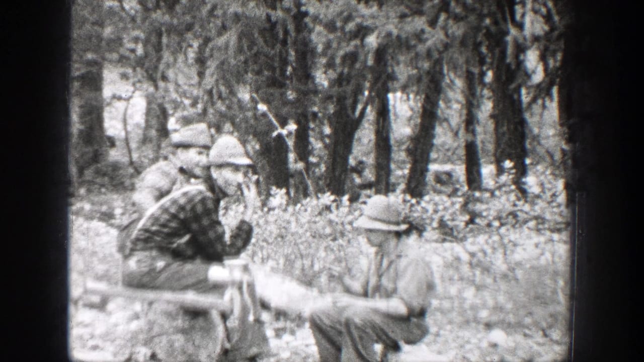 Men in hats gather in a wooded area near a rough outdoor table.