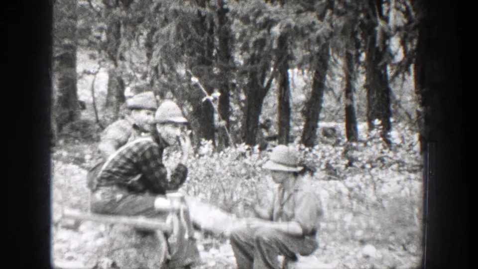 1939 Chelan, Washington 8mm frame showing men in hats gathered among trees beside an improvised outdoor cooking area.