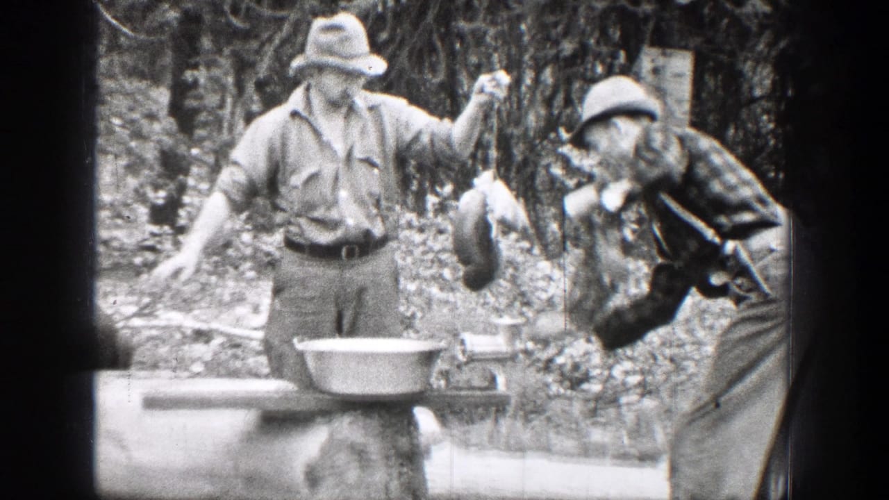 Two men outdoors with game meat, a grinder, and a metal pan in a wooded setting.