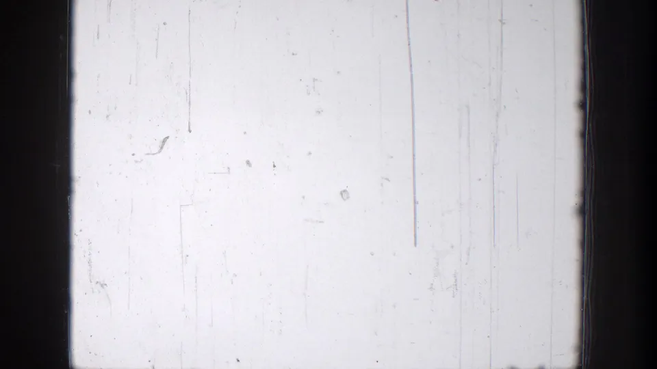 A pale 1939 8mm frame with film scratches, dark borders, and a faint edge of trees or hillside on the right.