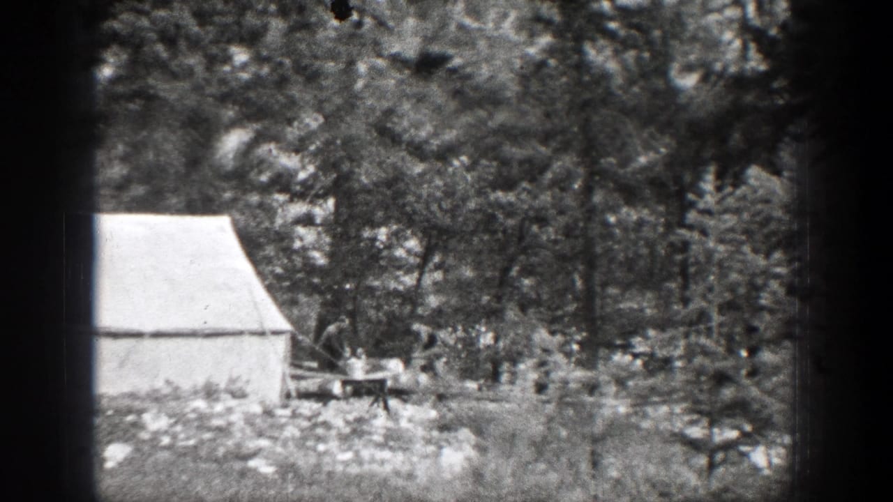 A white canvas tent stands in a forest clearing near Chelan, Washington, with trees, rocks, and a small work area visible in 1939 8mm footage.