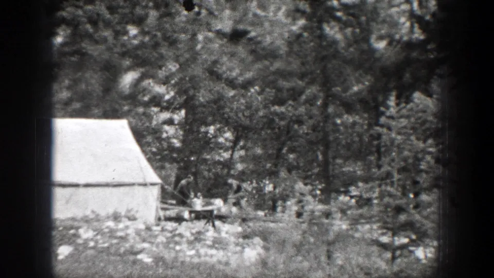 A white canvas tent stands in a forest clearing near Chelan, Washington, with trees, rocks, and a small work area visible in 1939 8mm footage.