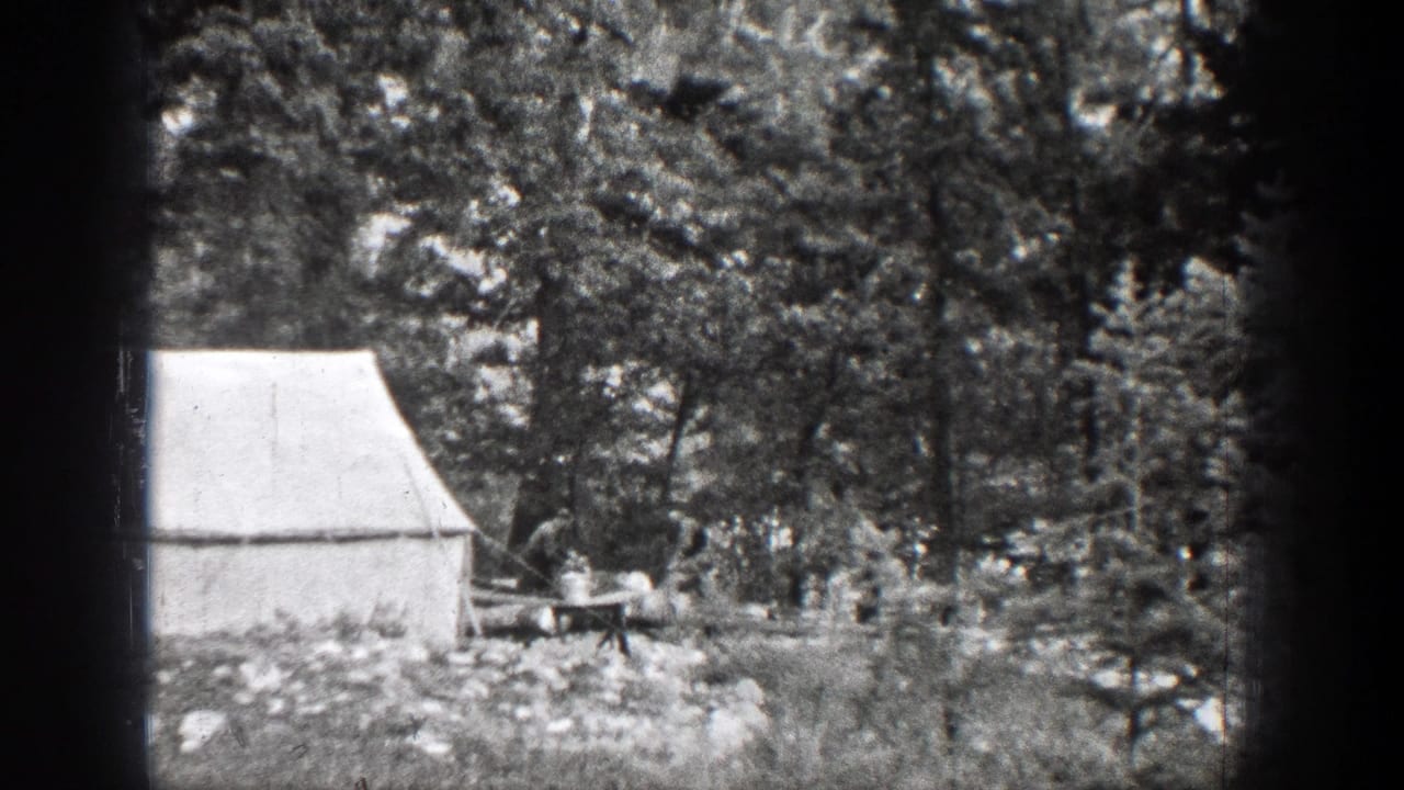 Canvas tent and wooded clearing with a small sawing area near the trees.