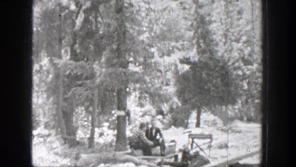 1939 Chelan, Washington home-movie frame showing people seated near a wooded shore beside the lake.
