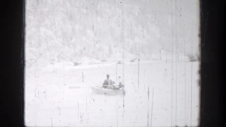 A small rowboat carrying two people appears near a pale shoreline in the 1939 Chelan lake footage.