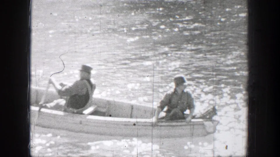 Closer Chelan lake view shows one person rowing while another sits in the bow of a small rowboat on sparkling water.