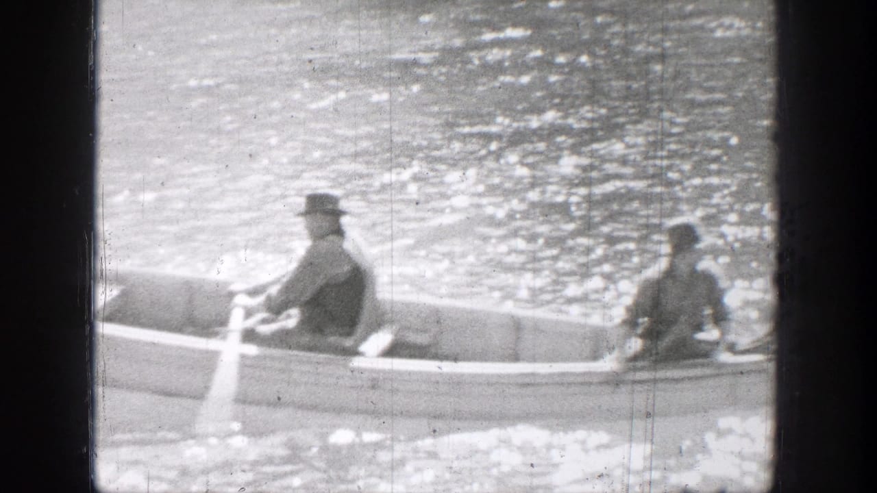 Two people in hats sit in a rowboat on bright rippling water.