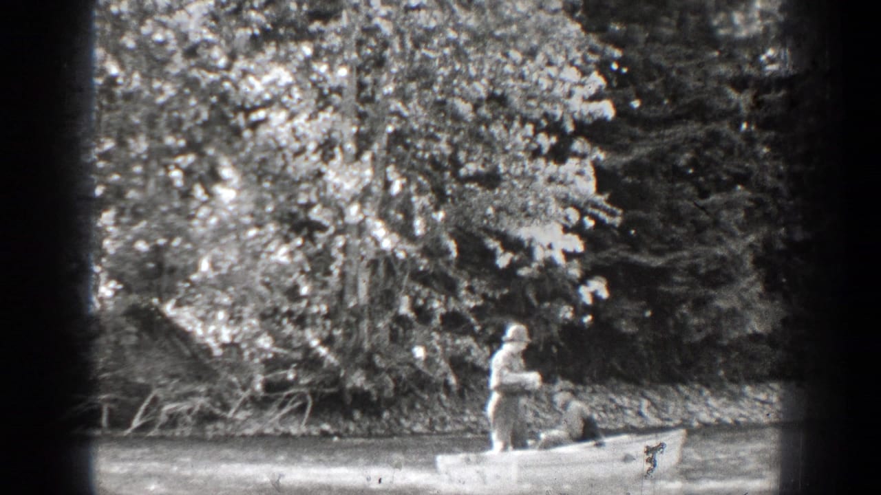 Man standing in a rowboat while another man sits near the bow.