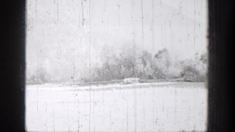 1939 Chelan, Washington home-movie frame showing a pale lake or snowy shoreline with distant trees and dark vertical edges.