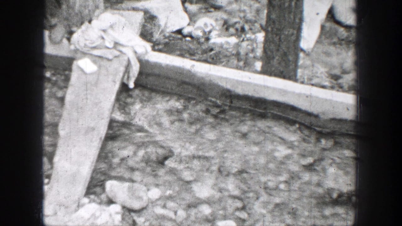 1939 Chelan, Washington view of a plank over running water, with rocks, boards, and fabric at the creek edge.