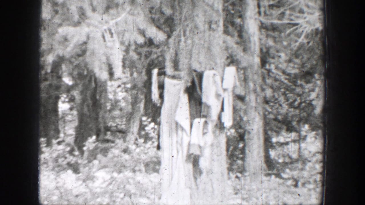 1939 Chelan, Washington home-movie frame showing laundry on a line among trees beside brush and creekside stones.